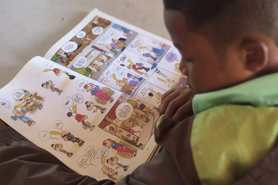 Enfant lisant une bande dessinée à l'orphelinat de Malaza