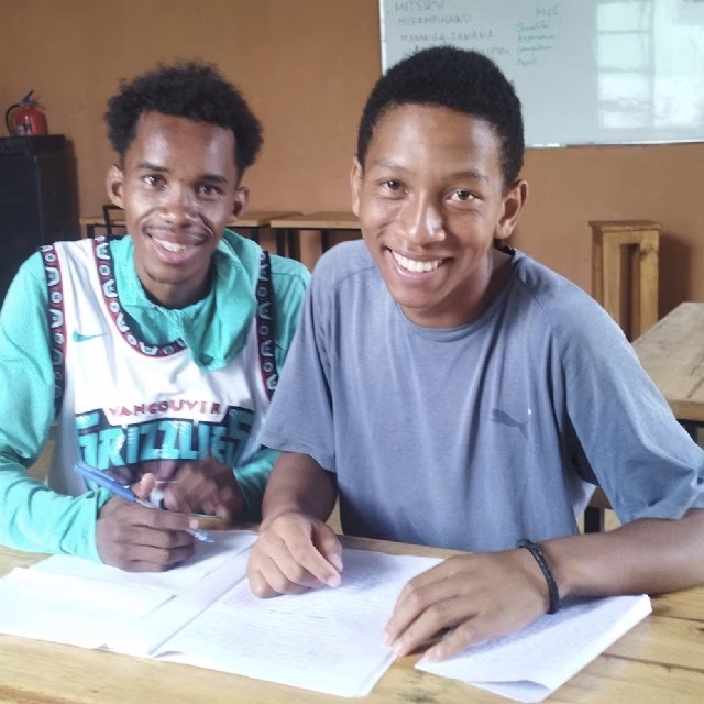 Deux jeunes souriants révisant ensemble à la Maison des Jeunes