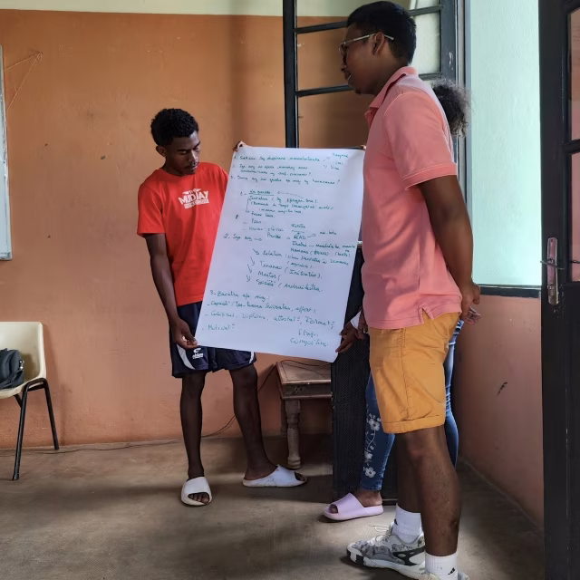 Deux jeunes présentent les résultats de leur travail de groupe sur un paperboard