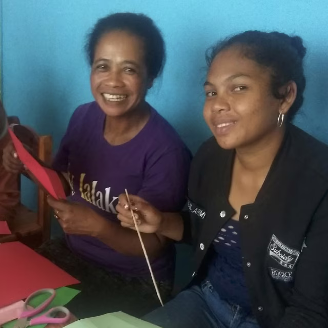 Deux éducatrices souriantes découpant du papier coloré lors de l'atelier de travaux manuels