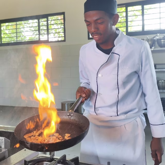 Victor réalise un flambé en cuisine professionnelle durant sa formation à l'École de Cuisine Aïna