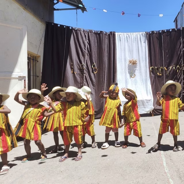 Enfants en tenues jaunes traditionnelles dansant ensemble à la maternelle d'Isotry