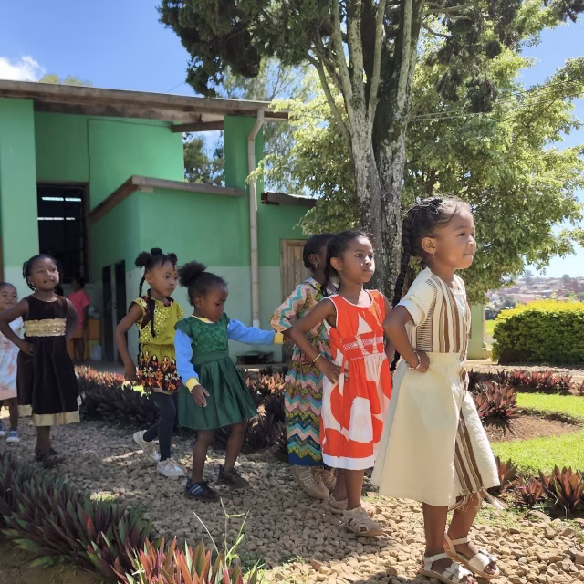 Fillettes en robes colorées dansant dans le jardin du Village Aïna