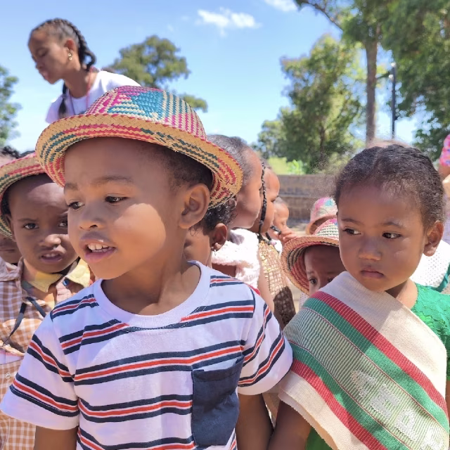 Enfants portant des chapeaux traditionnels en paille lors de la fête culturelle au Village Aïna