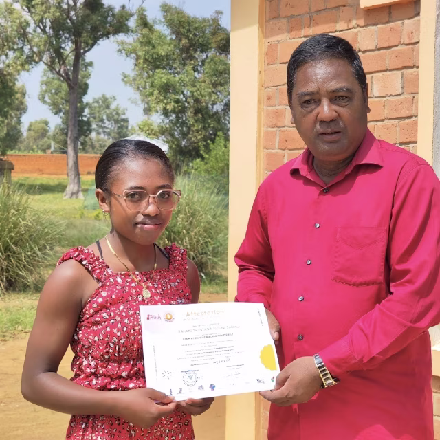 Une apprenante reçoit fièrement son attestation de fin de formation en couture au Village Aïna