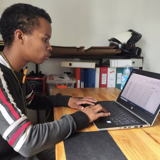 Jeune apprenant utilisant l'ordinateur dédié à la gestion pédagogique de l'École de Cuisine Solidaire