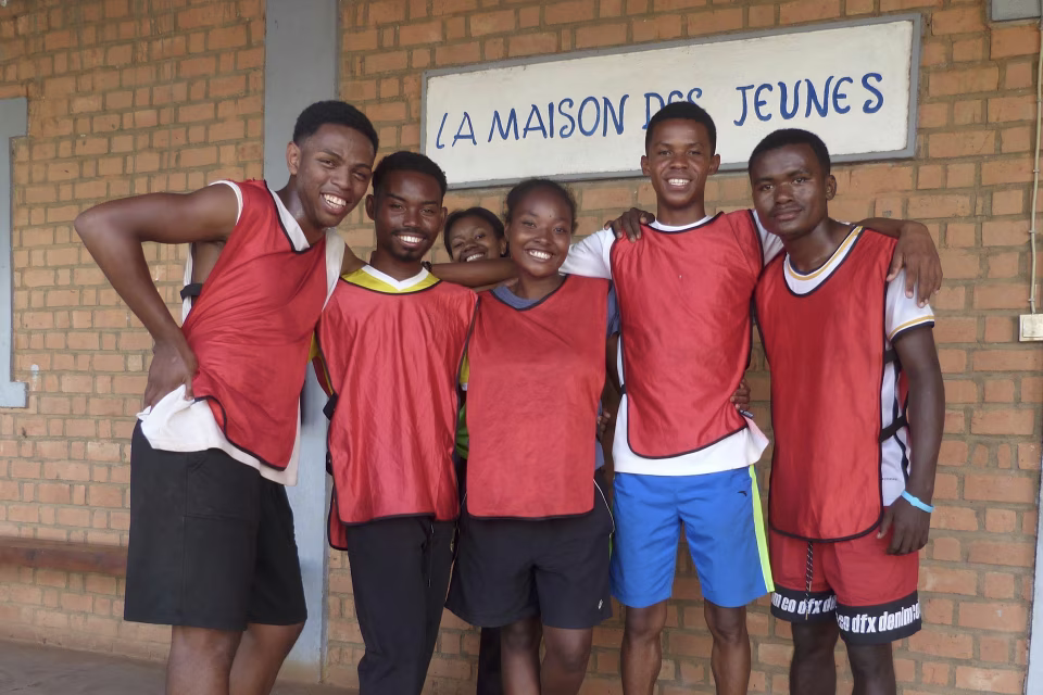 Jeunes de la Maison des Jeunes d'Aïna en maillots de sport devant le bâtiment