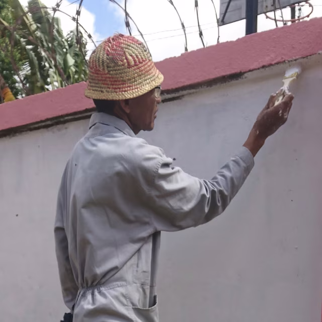 Ouvrier repeignant les murs d'enceinte de l'orphelinat de Malaza