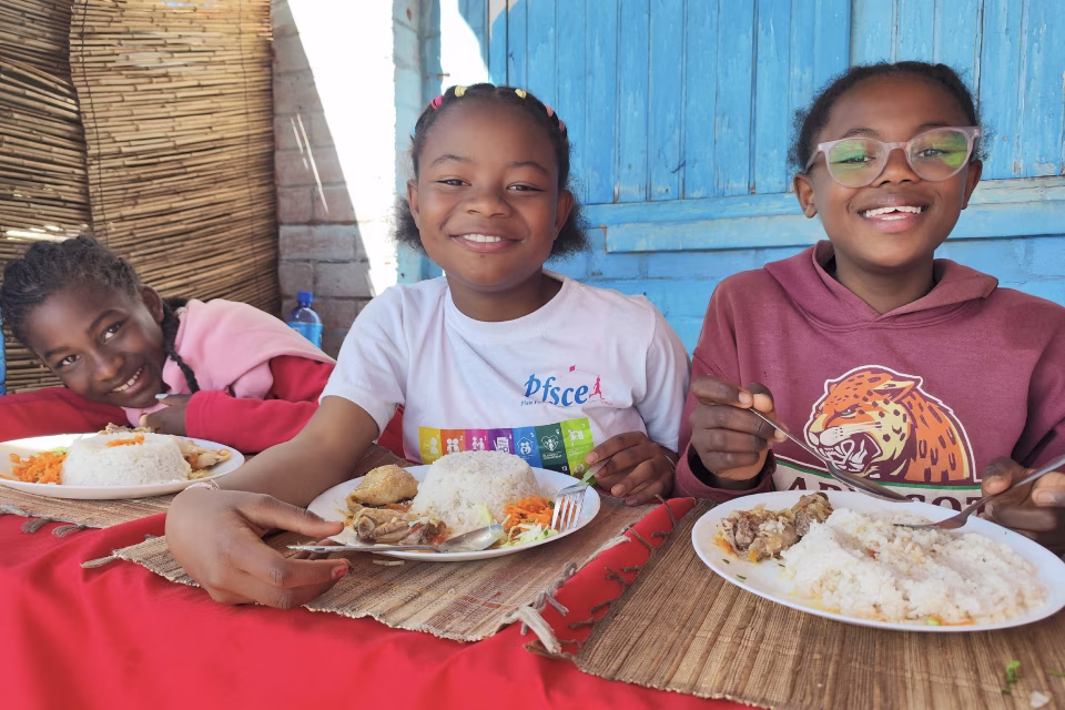 Enfants de l'orphelinat de Malaza partageant un repas équilibré en souriant