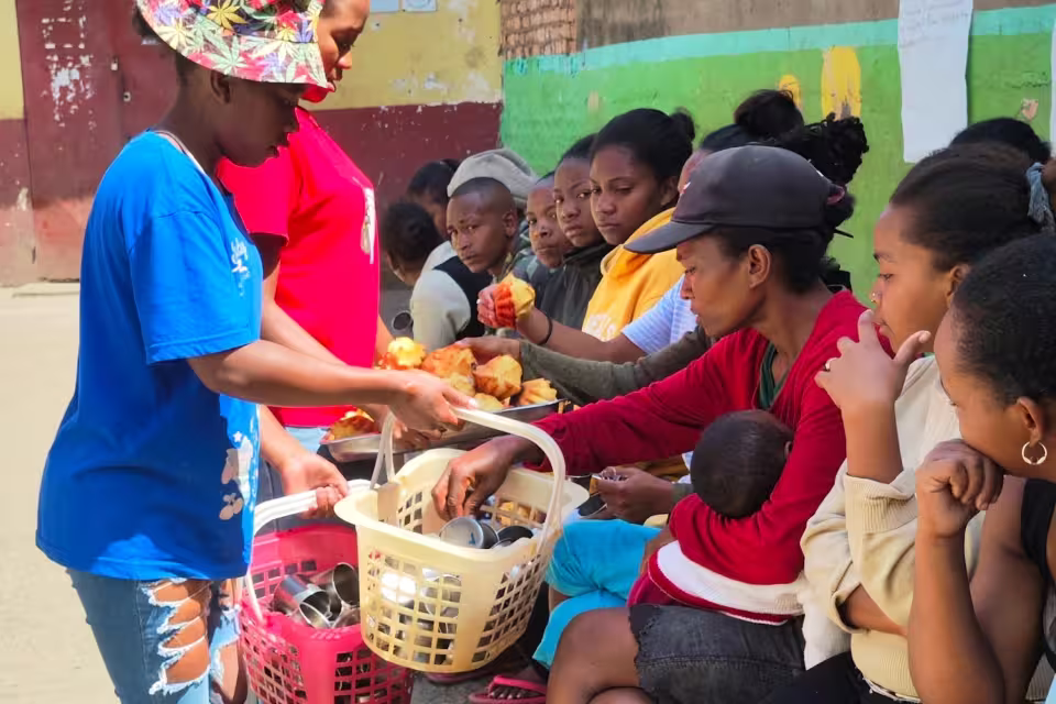 Distribution de la collation aux parents en fin d'atelier devant la maternelle solidaire d'Isotry, paniers remplis de timbales.