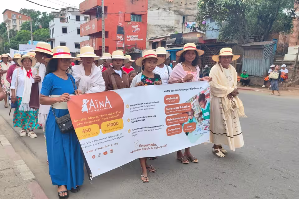 Une dizaine de femmes en formation au Centre de Couture Solidaire d'Aïna défilent dans les rues d'Antananarivo en portant la banderole de l'association lors du carnaval du 8 mars.