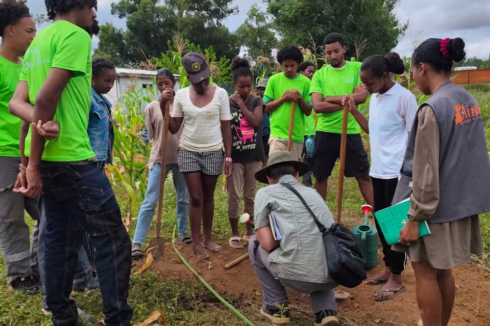 Étudiants en t-shirts verts du lycée agricole Formaterra rassemblés autour d'une démonstration au sol pendant l'immersion au Centre de Formation Agricole du Village Aïna.