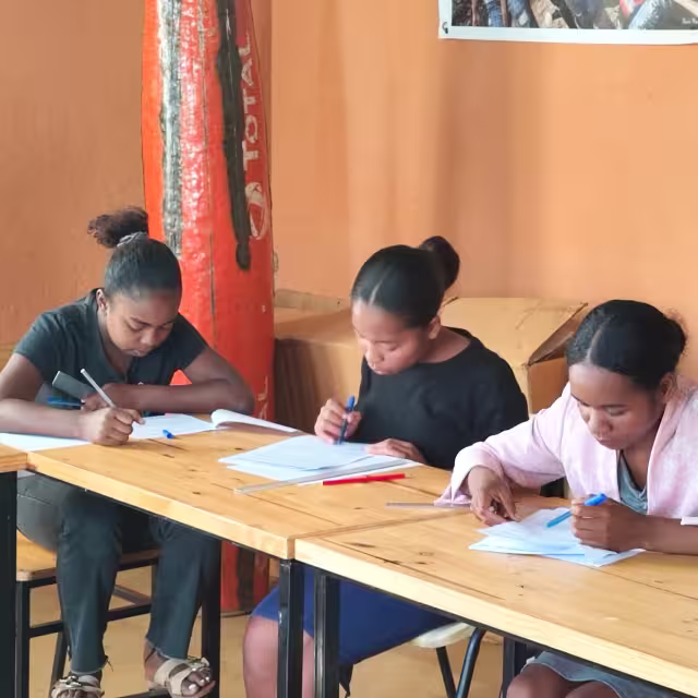 Trois stagiaires du CFSEP concentrées sur un exercice écrit dans leur cahier pendant la session de formation en classe.