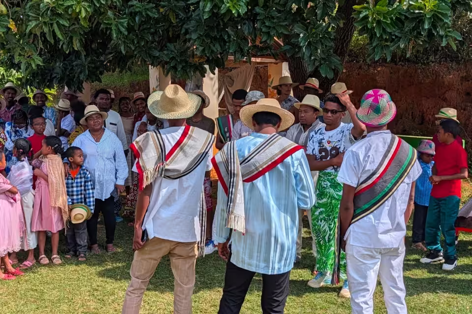 Groupe d'hommes en chemises blanches et écharpes aux couleurs malagasy (rouge, blanc, vert) lors du cérémonial du Taombaovao à Malaza.