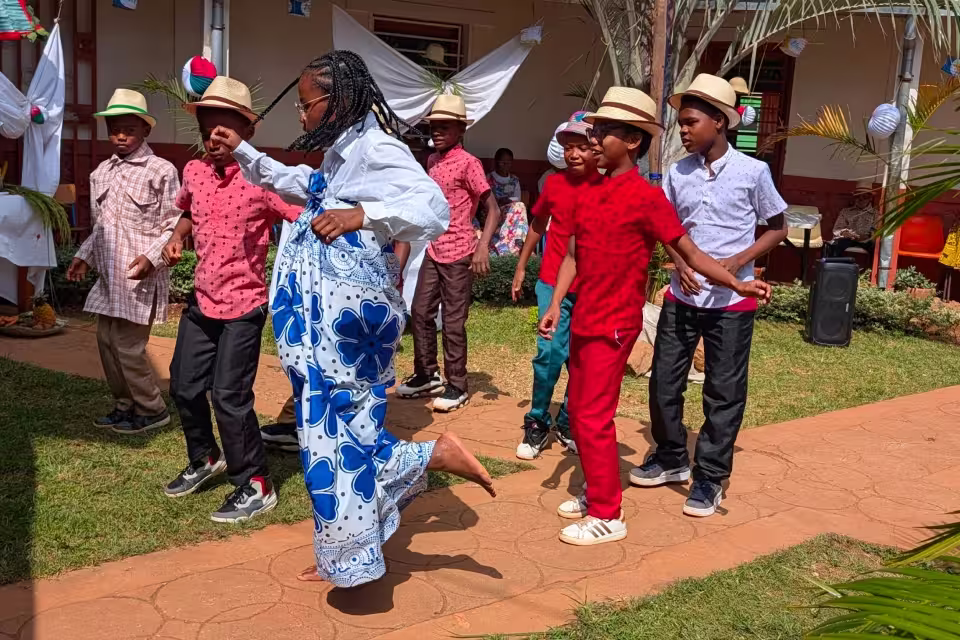 Enfants de Malaza dansant en cercle à l'ombre d'un arbre lors des animations culturelles du Taombaovao Malagasy.