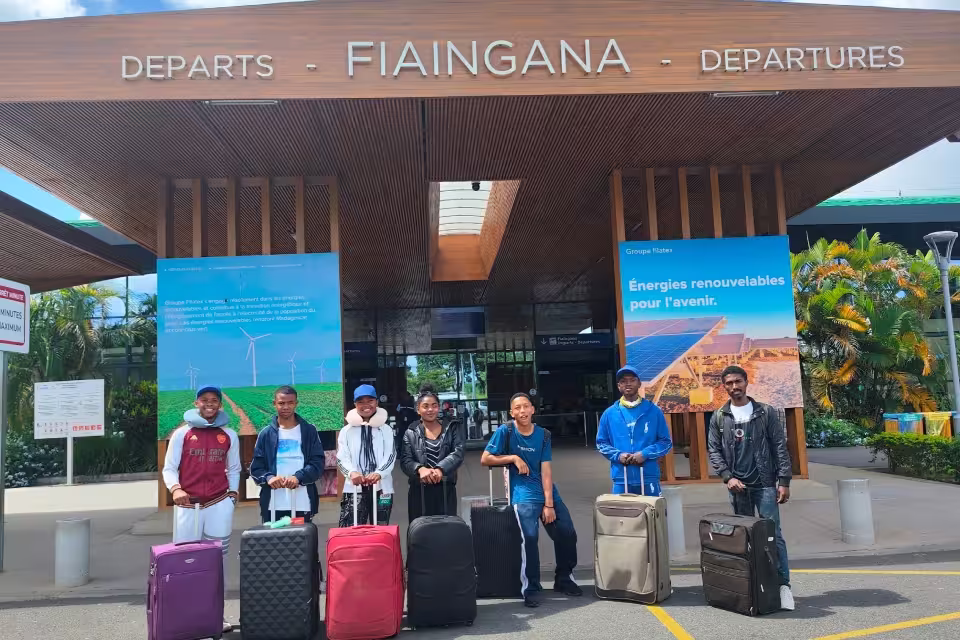 Les jeunes d'Aïna et leurs encadrants posent avec leurs valises devant le hall des départs de l'aéroport d'Ivato à Antananarivo, avant le vol pour La Réunion.