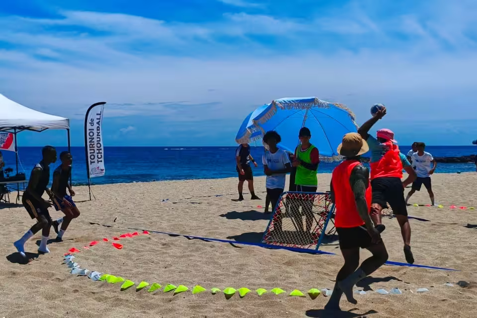 Match de beach tchoukball en cours sur la plage de La Réunion, un joueur d'Aïna en plein tir devant le filet du tournoi.
