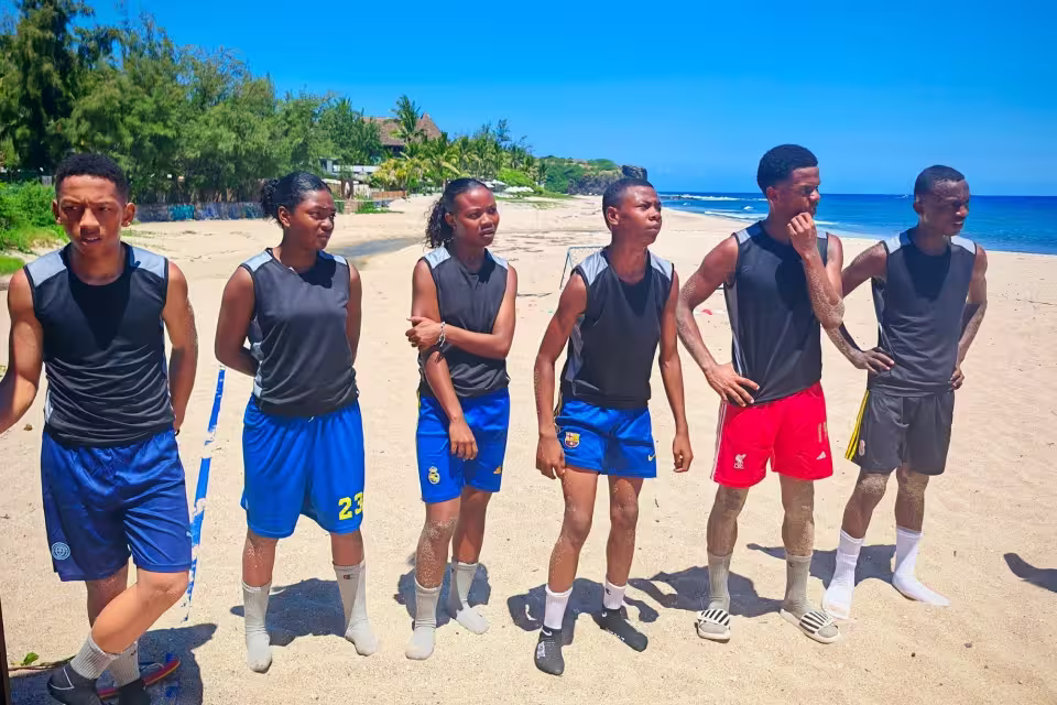 Les 6 jeunes sélectionnés marchent ensemble sur la plage de La Réunion, en tenue de match, avant une rencontre du tournoi.