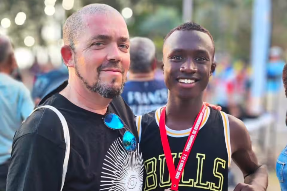 Portrait souriant d'un jeune joueur d'Aïna avec un accompagnant, médaille du tournoi de tchoukball des 7 et 8 mars 2026 autour du cou.