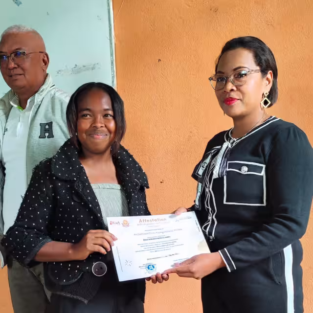 Une diplômée reçoit son attestation des mains d'une représentante des autorités locales lors de la cérémonie