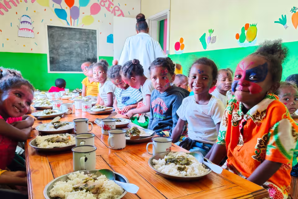 Enfants de maternelle Aïna aux visages peints déjeunant ensemble à la cantine lors d'un jour de fête