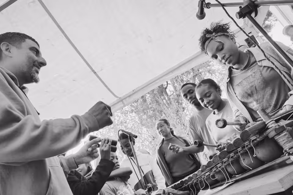 Musicien de Dia Dia Maloya guidant des jeunes adolescents au balafon lors d'un atelier sous le chapiteau
