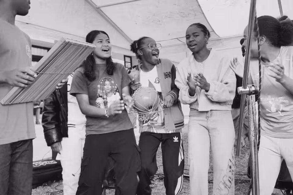 Jeunes filles enthousiastes chantant et jouant des percussions sous le chapiteau lors du concert maloya