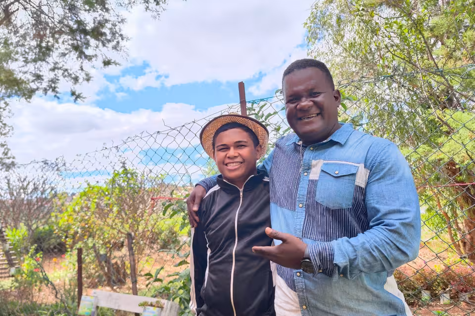 Un adolescent d'Aïna et un adulte complices, souriants dans le jardin du Village après le concert