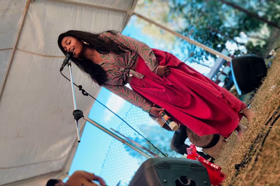 La chanteuse de Dia Dia Maloya interprète un chant maloya au micro en robe rose sur la scène