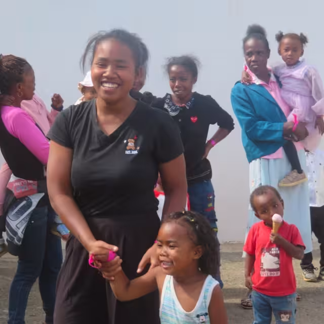 Une maman souriante tient la main de sa petite fille lors de la journée récréative à Bouba Sport