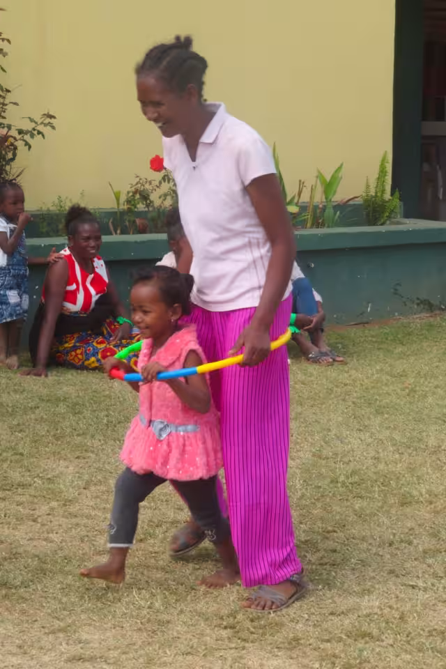Une maman et sa fille jouent avec un bâton coloré sur la pelouse lors des activités en famille