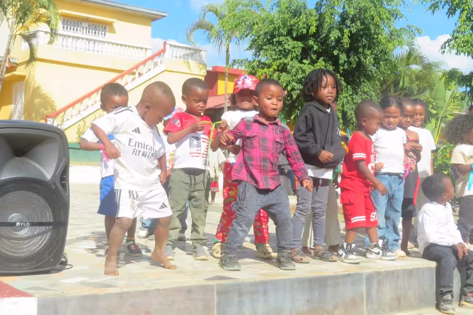 Des enfants de maternelle dansent sur une petite scène en plein air lors de la fête récréative à Bouba Sport