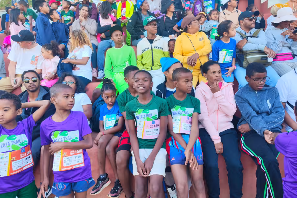 Jeunes d'Aïna avec dossards Zaza Trail assis dans les tribunes, attendant le départ de la course