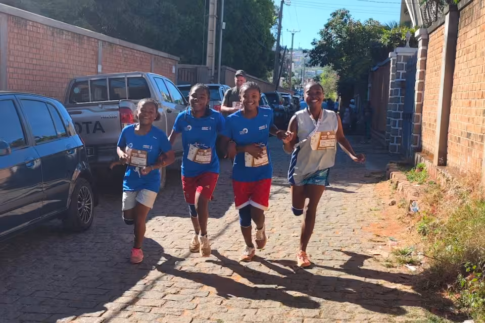 Quatre jeunes filles d'Aïna courant et souriant dans une rue pavée lors de l'UTOP 2026