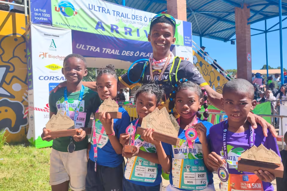 Jeunes lauréats d'Aïna brandissant leurs trophées devant le panneau d'arrivée de l'UTOP 2026