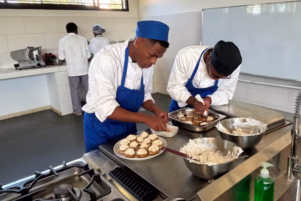 Jeunes en formation à l'École de Cuisine Solidaire Aïna décorant des pâtisseries dans le laboratoire pédagogique