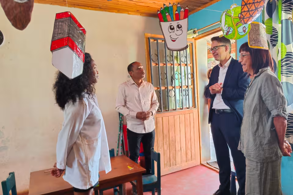 L'Ambassadeur d'Allemagne et son accompagnatrice en échange avec une bénéficiaire dans une salle d'activités Aïna