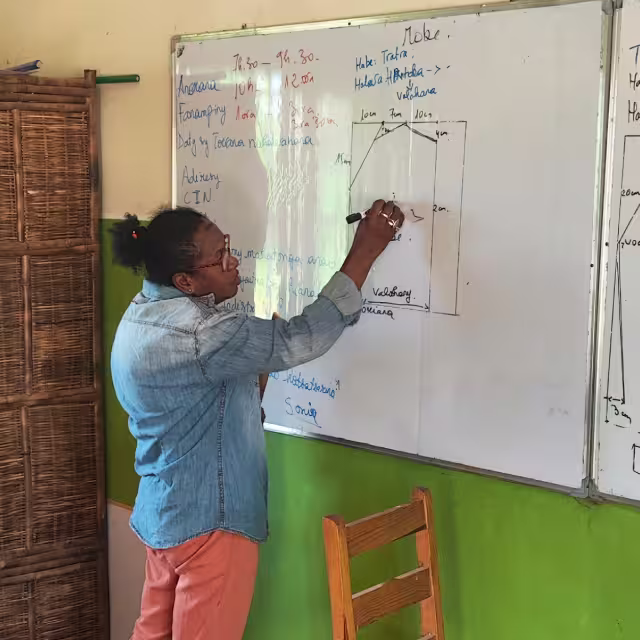 Une formatrice du Centre de Formation Solidaire en Couture explique un tracé de patron au tableau