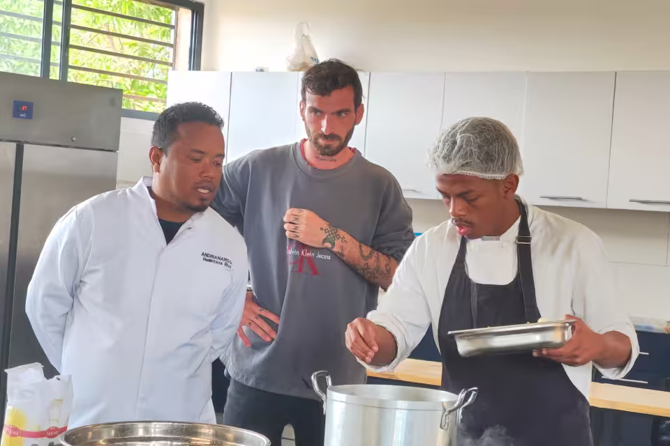 Le chef formateur et un intervenant observent un élève de l'École de Cuisine Solidaire pendant son épreuve