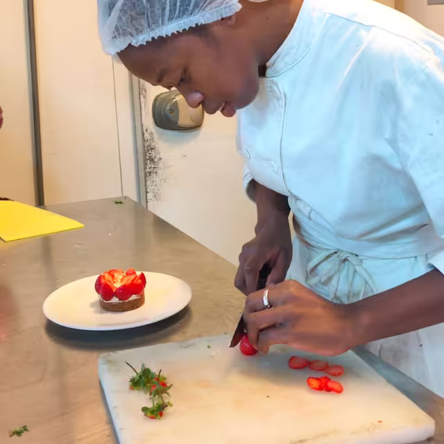 Une élève de l'École de Cuisine Solidaire dresse une tartelette aux fraises