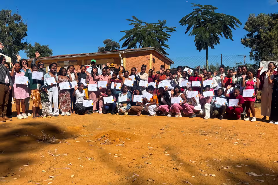 Une promotion du Centre de Formation Solidaire pose avec les attestations de fin de formation devant le centre