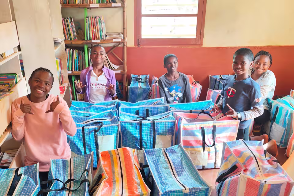 Des enfants de Malaza posent avec les sacs de voyage préparés pour le départ en colonie