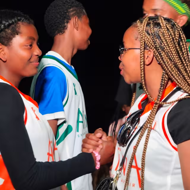 Deux jeunes se serrent la main après le match, en maillot aux couleurs d'Aïna