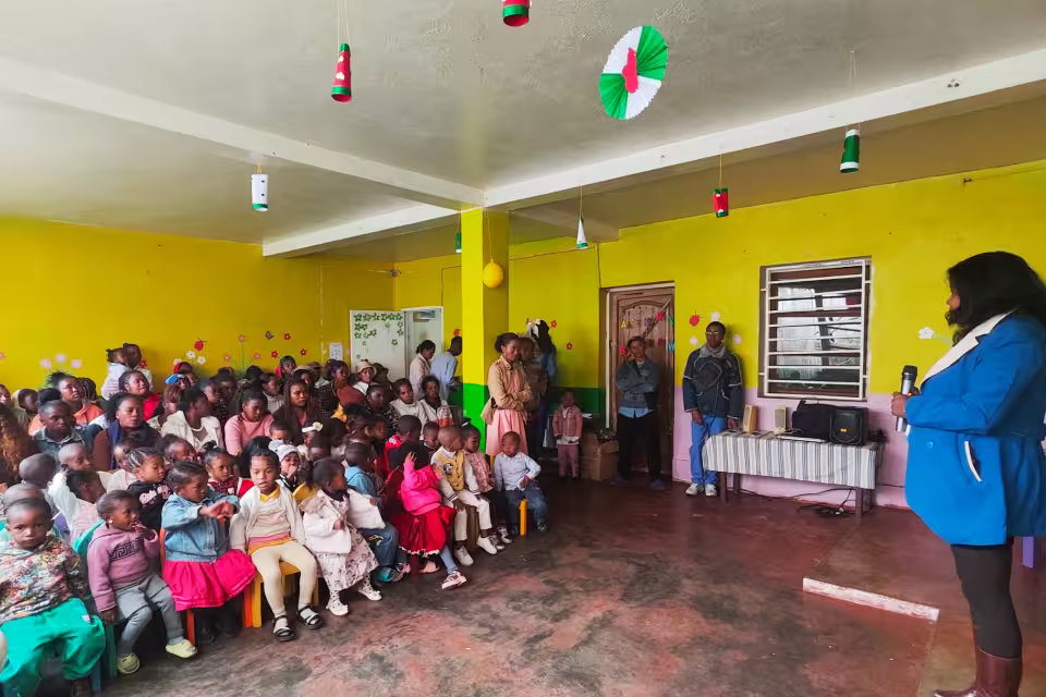 Enfants et parents réunis dans la salle de la maternelle solidaire pour la célébration de fin d'année scolaire
