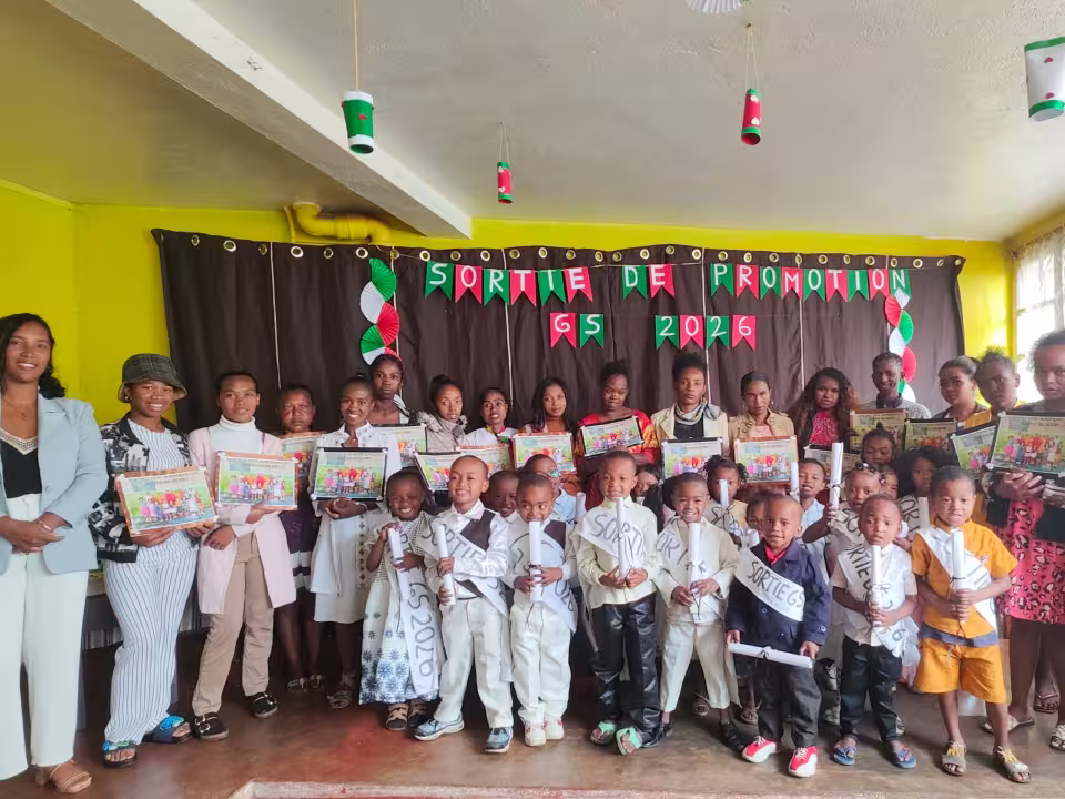 Les enfants de Grande Section de la maternelle solidaire d'Isotry et leurs éducatrices posent avec les certificats de la sortie de promotion 2026